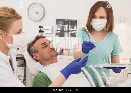 Female dentist examining patient avec assistant dentaire, Munich, Bavière, Allemagne Banque D'Images