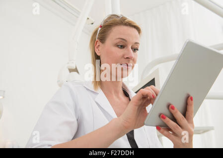 Female dentist using digital tablet in clinique, Munich, Bavière, Allemagne Banque D'Images