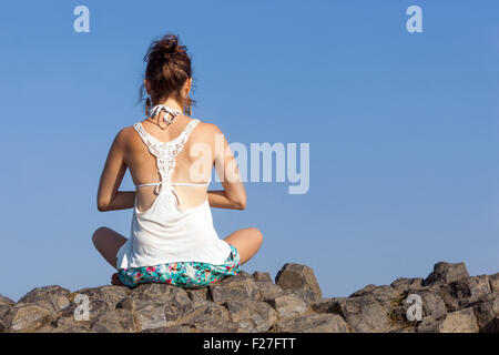 Femme yoga pose sur la roche volcanique vue arrière Banque D'Images