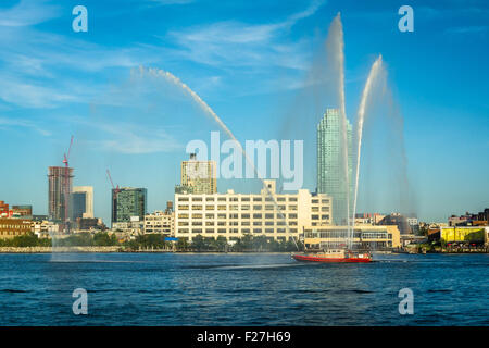 Bateau feu pulvériser de l'eau au cours de l'East River, vu de Roosevelt Island, à Manhattan, New York. Banque D'Images