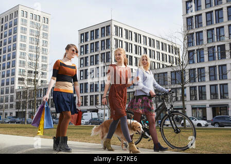 Trois amis marchant dans une aire de jeux avec chien, Munich, Bavière, Allemagne Banque D'Images