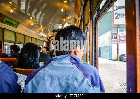 Un passager asiatique sur le Fleuve Charles Streetcar regarde par la fenêtre à New Orleans, LA Banque D'Images