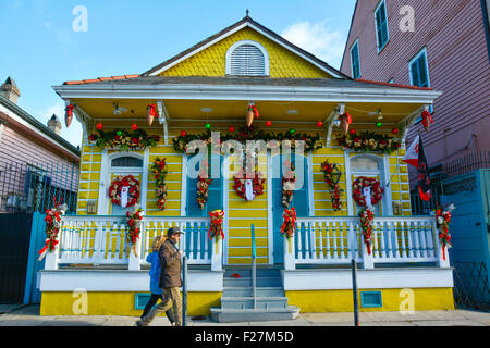 Un couple marche passé un cottage créole décorée dans Garland et couronnes pour les vacances dans le quartier français de New Orleans, LA Banque D'Images