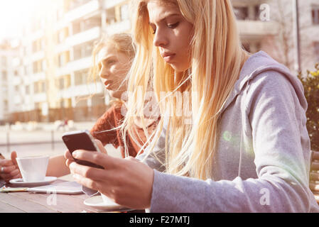 Teenage girl text messaging at sidewalk cafe, Munich, Bavaria, Allemand Banque D'Images