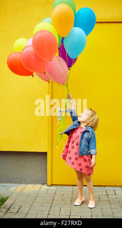 Happy little girl outdoors with balloons Banque D'Images