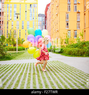 Happy little girl outdoors with balloons Banque D'Images