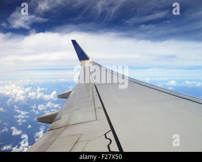 Aile d'avion et nuageux ciel bleu lors d'un vol. Banque D'Images