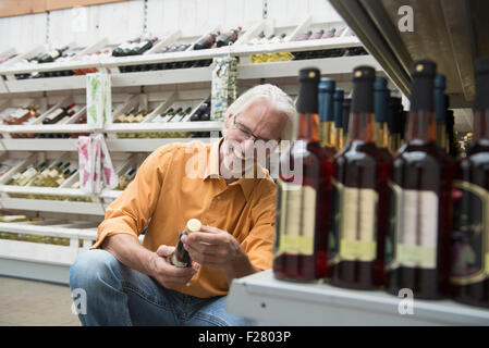 Lecture client étiquette sur bouteille de vin en supermarché, Augsbourg, Bavière, Allemagne Banque D'Images