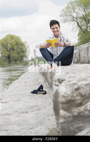 Mature Woman sitting on steps and reading book, Bavière, Allemagne Banque D'Images