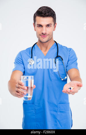 Portrait of a happy male doctor holding glass avec de l'eau et comprimé isolé sur fond blanc Banque D'Images