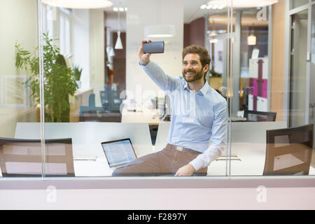 Businessman selfies à prendre des photos en open space office Banque D'Images