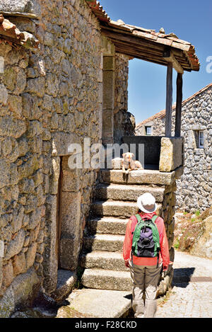 Portugal : Femme à la recherche de chien à l'escalier d'une maison en pierre dans le village historique de Monsanto Banque D'Images