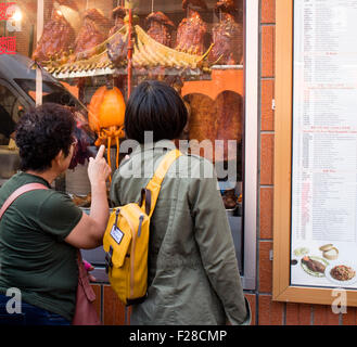 Chinese woman looking at croustillant de canard dans le fenêtre. Gerrard Street, London UK Banque D'Images