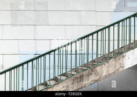 Escalier urbain avec garde-corps en métal vert sur mur de béton blanc Banque D'Images