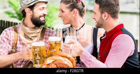 Les gens avec de la bière et bretzel dans Bavarian inn manger et boire Banque D'Images