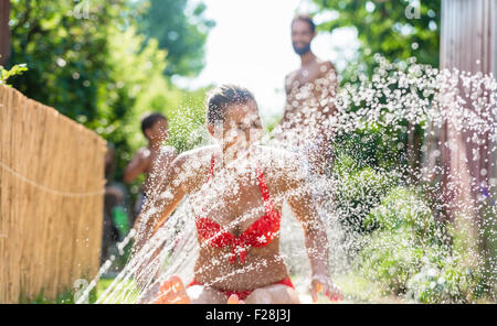 Refroidissement de la famille vers le bas avec le jardin de sprinkleur, beaucoup d'eau éclaboussant autour Banque D'Images