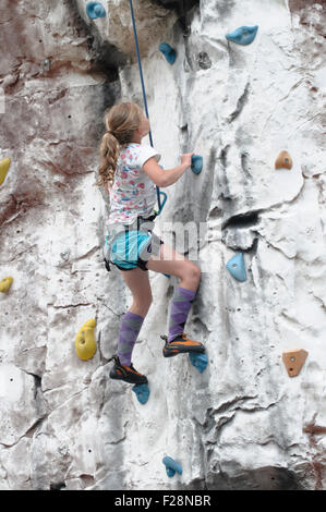 Young teen girl grimpe un mur d'escalade artificiel Banque D'Images