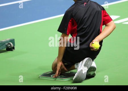 Ballboy à genoux sur le côté d'un court de tennis Banque D'Images