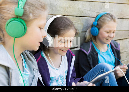 Trois amis assis dans une aire de jeux et d'écoute de la musique, Munich, Bavière, Allemagne Banque D'Images