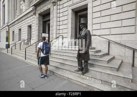 Sculpture d'Abraham Lincoln sur les marches de la Société historique de New York comme un jeune homme afro-américain passe devant. Banque D'Images