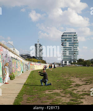 Les gens de l'ancienne bande de mort à l'East Side Gallery avec un nouveau bloc d'appartements de luxe derrière, Berlin, Allemagne Banque D'Images