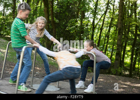 Les enfants s'amusant sur un carrousel en aire de jeux, Munich, Bavière, Allemagne Banque D'Images