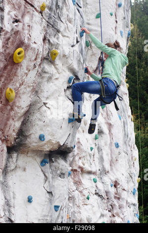Young teen girl grimpe un mur d'escalade artificiel Banque D'Images
