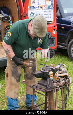 Un maréchal-ferrant la préparation d'un fer à cheval pour le montage à l'Essex Show, Barleylands, Essex. Banque D'Images