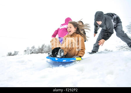 Fille obtient vers le bas de la colline de neige en traîneau Banque D'Images