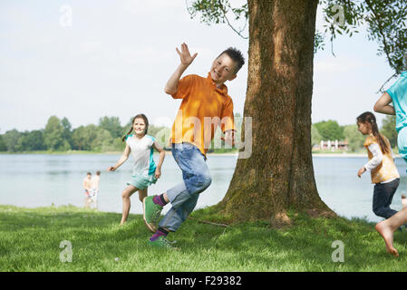 Les enfants courent autour d'un arbre au Lakeshore, Bavière, Allemagne Banque D'Images