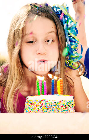 Birthday girl blowing out candles on cake Banque D'Images