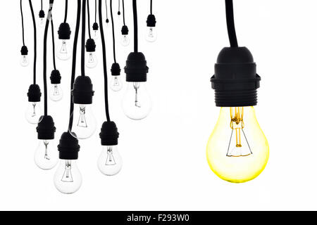 Une ampoule jaune à côté d'un certain nombre d'ampoules hanging on white Banque D'Images