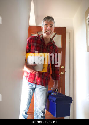 Technicien OUVRIER DOMESTIQUE IPAD Happy smiling commerçant avec l'iPad d'arriver à ouvrir la porte de la maison pour des travaux d'entretien de chaudière réparation sécurité Banque D'Images