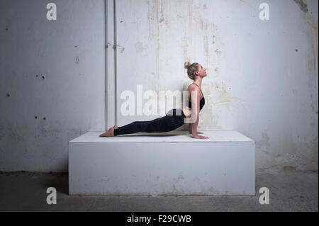 Mid adult woman practicing cobra position sur les blocs de béton, Munich, Bavière, Allemagne Banque D'Images