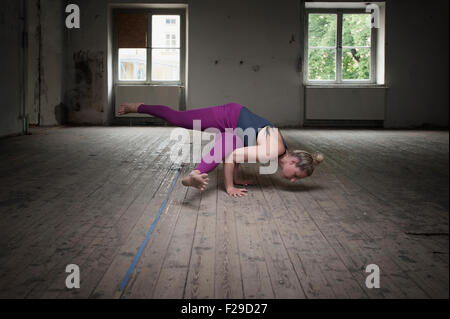 Mid adult woman practicing Eka pada koundinyasana je pose dans un studio de yoga, Munich, Bavière, Allemagne Banque D'Images