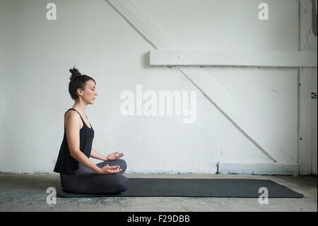 Portrait of a Mid adult woman in yoga studio pose lotus, Munich, Bavière, Allemagne Banque D'Images