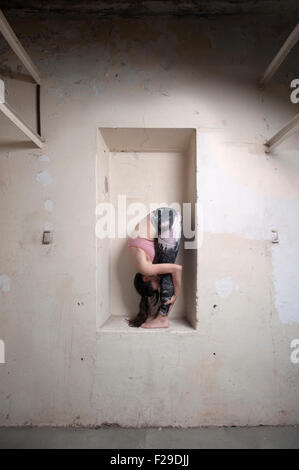 Mid adult woman practicing uttanasana posent dans une alcôve, Munich, Bavière, Allemagne Banque D'Images