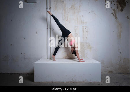 Mid adult woman pratiquant une pattes chien tête en bas position sur les blocs de béton, Munich, Bavière, Allemagne Banque D'Images