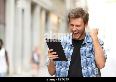 Des cris de l'homme gagnant euphorique une tablette dans la rue Banque D'Images