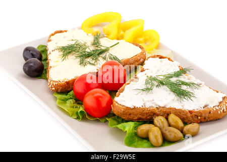 Sandwiches avec des légumes frais, des olives, du beurre et du fromage sur la plaque. Banque D'Images