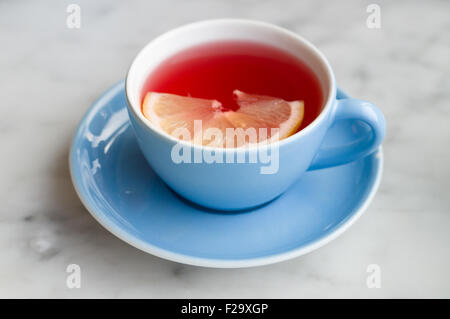 Plateau de fruits rouge avec tranche de citron en bleu tasse Banque D'Images