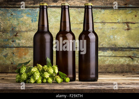 Trois bouteilles de bière avec la branche de houblon sur fond de bois Banque D'Images