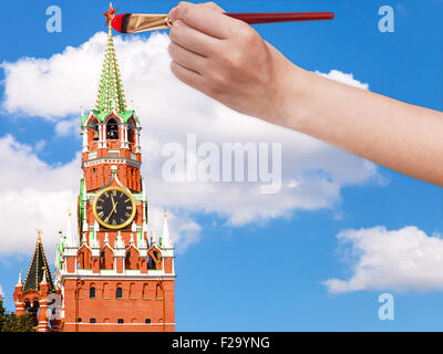 Travel Concept - la main avec des peintures pinceau l'étoile rouge sur la tour Spasskaya du Kremlin de Moscou Banque D'Images