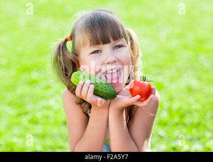 Heureux l'enfant sur l'herbe prêt avec des légumes sains dans ses mains Banque D'Images