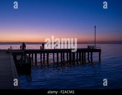 Silhouettes de personnes debout sur un quai au coucher du soleil, Victoria, Australie Banque D'Images