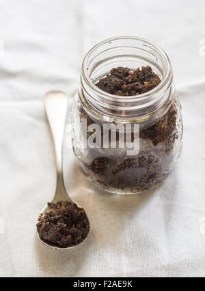 Des soins du visage et du corps, à toutes les matières organiques (peeling gommage café) dans un bocal de verre placé sur un fond clair. Déposer sur le côté Banque D'Images