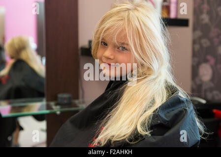 Coupe Coiffure féminine et le brossage du jeune enfant fille blonde cheveux dans le salon de coiffure Banque D'Images