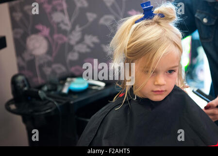 Coupe Coiffure féminine et le brossage du jeune enfant fille blonde cheveux dans le salon de coiffure Banque D'Images