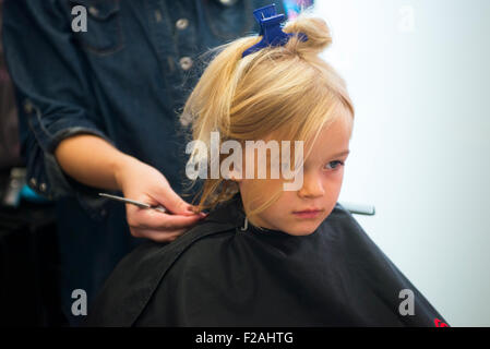 Coupe Coiffure féminine et le brossage du jeune enfant fille blonde cheveux dans le salon de coiffure Banque D'Images