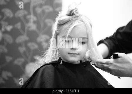 Coupe Coiffure féminine et le brossage du jeune enfant fille blonde cheveux dans le salon de coiffure Banque D'Images